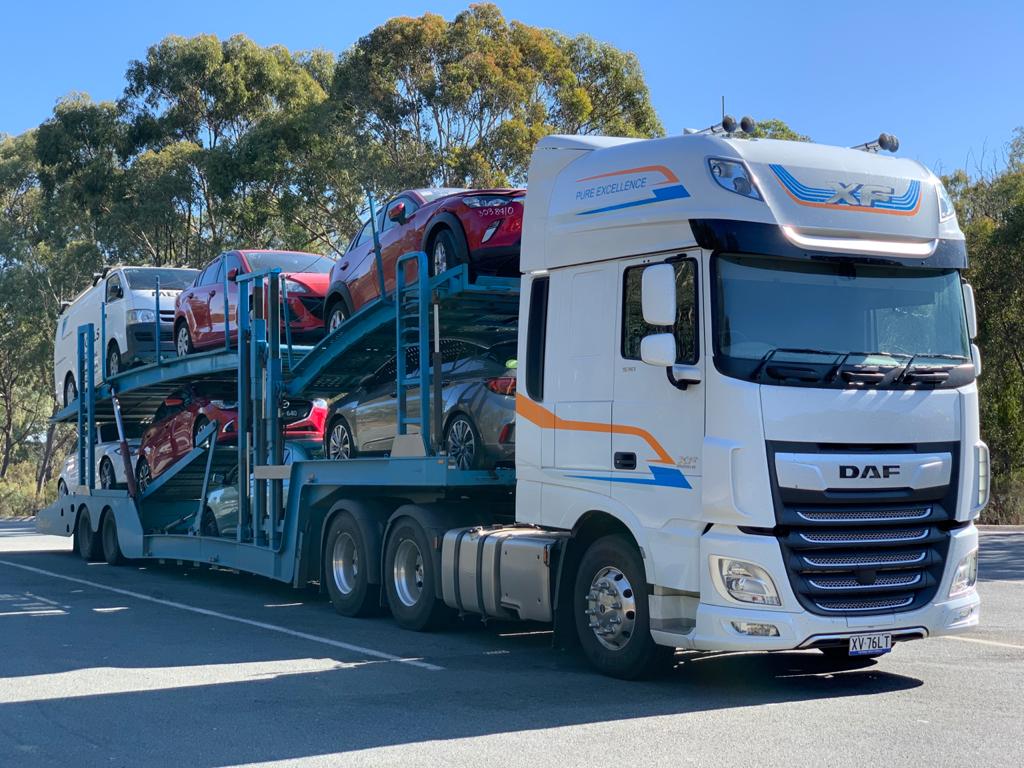 Auto Mover Multi-Level Car Carrier Transporting Red Vehicles
